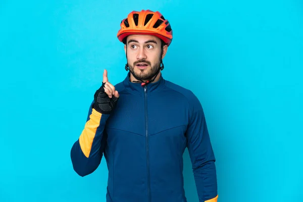 Joven Ciclista Aislado Sobre Fondo Azul Pensando Una Idea Apuntando — Foto de Stock