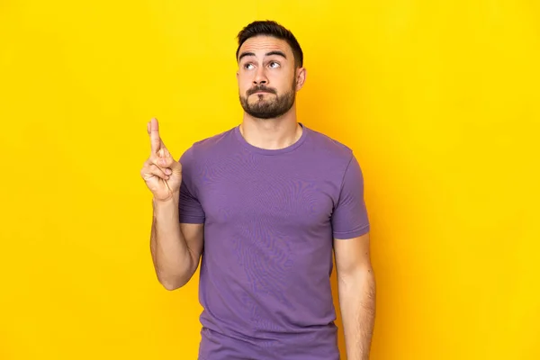 Jovem Caucasiano Bonito Homem Isolado Fundo Amarelo Com Dedos Cruzando — Fotografia de Stock