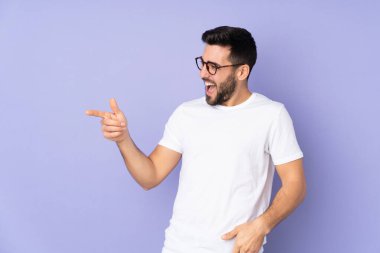 Kafkasyalı yakışıklı bir adam izole edilmiş arka planda. Parmakla göstererek bir ürün sunuyor.