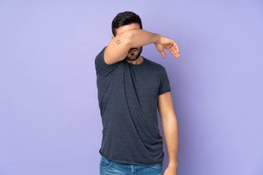 İzole edilmiş mor arka plan üzerinden gözlerini kapayan beyaz yakışıklı bir adam.