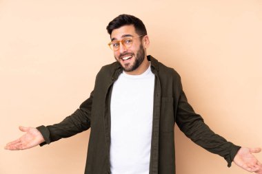 Beyaz tenli yakışıklı adam bej arka planda izole edilmiş mutlu ve gülümsüyor.
