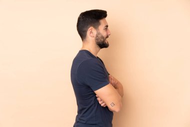 Beyaz tenli yakışıklı adam bej arka planda yalıtılmış, yan pozisyonda.