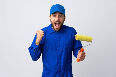 Beyaz arka planda izole edilmiş bir boya silindiri tutan ressam galibiyeti kutluyor.