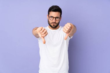 Kafkasyalı yakışıklı adam izole edilmiş arka planda baş parmağını iki eliyle aşağı gösteriyor.