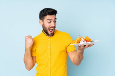 Mavi arka planda gözleme tutan beyaz adam zaferi kutluyor.