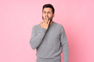 Kafkas yakışıklı adam izole edilmiş arka planda esniyor ve geniş ağzını eliyle kapatıyor.