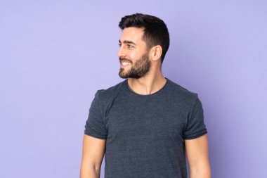 Beyaz tenli yakışıklı adam, yalıtılmış mor arka plana bakıyor.