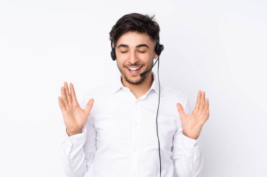 Beyaz arka planda izole edilmiş kulaklıkla çalışan pazarlamacı Arap adam gülüyor.