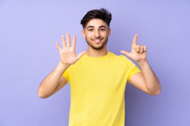 İzole edilmiş arka planda yaşayan Arap yakışıklı adam parmaklarıyla yediyi saydı.