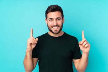 Beyaz tenli yakışıklı adam mavi arka planda izole edilmiş. Harika bir fikre işaret ediyor.