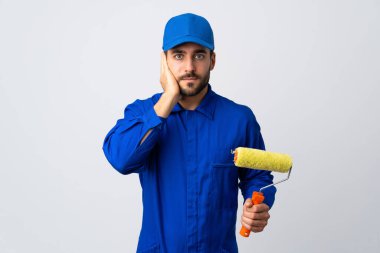 Beyaz arka planda izole edilmiş bir boya silindiri tutan ressam hayal kırıklığına uğramış ve kulaklarını kapatmış.