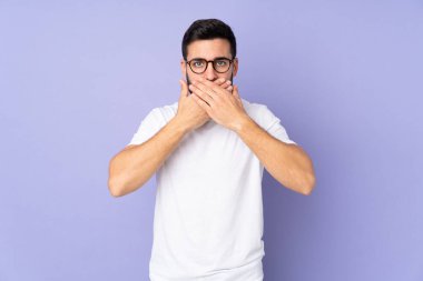 Kafkasyalı yakışıklı adam izole edilmiş arka planda ağzı elleriyle kapatıyor.