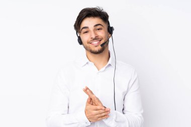 Beyaz arka planda izole edilmiş kulaklıkla çalışan pazarlamacı Arap adam alkışlıyor.