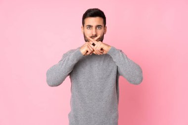 Kafkasyalı yakışıklı adam izole edilmiş arka planda sessizlik işareti gösteriyor.