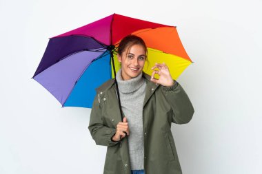 Beyaz arka planda şemsiye tutan genç bir kadın parmaklarıyla tamam işareti gösteriyor.