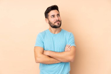 Beyaz tenli yakışıklı adam bej arka planda izole edilmiş, yan tarafa bakıyor.