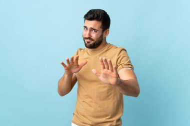 Arka planda sakallı yakışıklı bir genç adam. Ellerini öne uzatıyor.