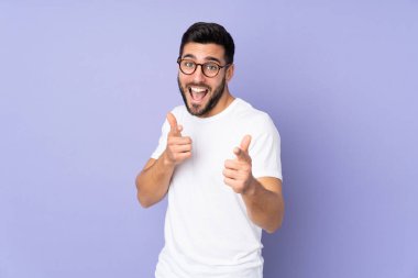 Kafkasyalı yakışıklı, soyutlanmış arka planda şaşırmış ve ön tarafı işaret ediyor.