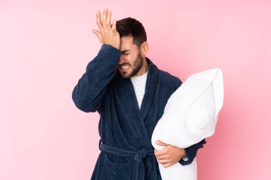 Genç adam pembe arka planda yalnız uyuyacak. Kafası karışık bir yüz ifadesi var.