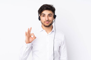 Tele pazarlamacı Arap bir adam beyaz arka planda izole edilmiş bir kulaklıkla çalışıyor.