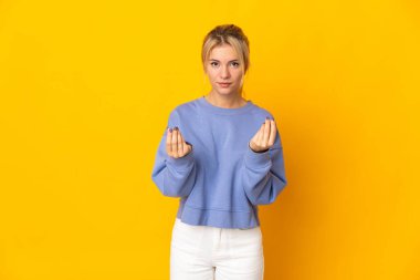 Sarı arka planda izole edilmiş genç bir Rus kadın para hareketi yapıyor ama mahvolmuş.