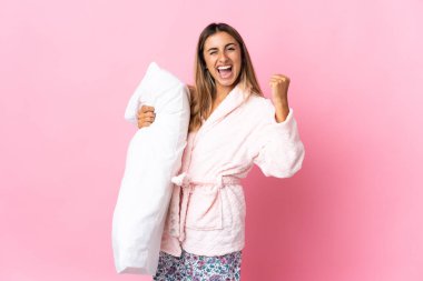 Pijamalı, pembe arka planda genç bir İspanyol kadın elinde yastıkla zaferi kutluyor.