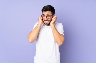 Kafkasyalı yakışıklı adam izole edilmiş arka planda hayal kırıklığına uğramış ve kulaklarını kapatmış.