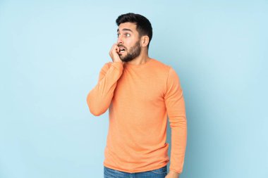 Beyaz tenli yakışıklı adam, izole edilmiş mavi arka plan yüzünden biraz gergin.