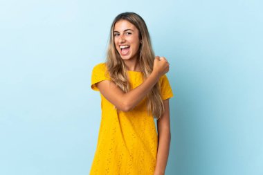 Genç İspanyol kadın, izole edilmiş mavi arka planda zaferi kutluyor.
