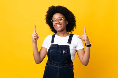 Sarı arka planda izole edilmiş genç Afrikalı Amerikalı kadın harika bir fikre işaret ediyor.