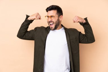 Beyaz tenli yakışıklı adam bej arka planda izole edilmiş güçlü bir jest yapıyor.