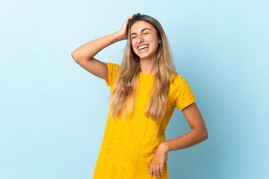 İzole edilmiş mavi arka planı olan genç İspanyol kadın çok gülümsüyor.