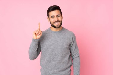 Kafkasyalı yakışıklı adam izole edilmiş arka planda en iyinin işareti olarak parmağını kaldırıyor ve gösteriyor.