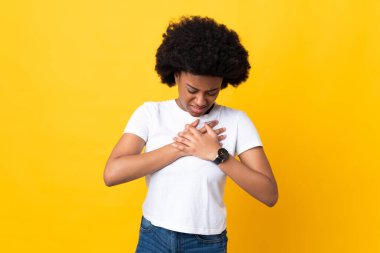 Sarı arka planda izole edilmiş genç Afrikalı Amerikalı bir kadın. Kalbinde ağrı var.