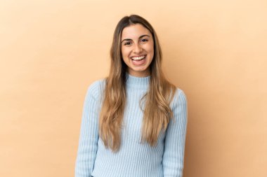 Beyaz tenli genç bir kadın, bej arka planda izole edilmiş ve yüzünde sürpriz bir ifade var.