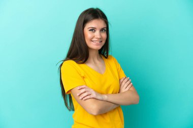 Mavi arka planda izole edilmiş, kolları çapraz ve ileriye bakan beyaz bir kadın.