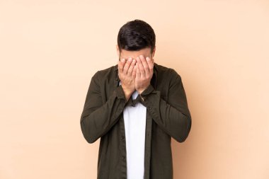 Beyaz tenli yakışıklı adam bej arka planda izole edilmiş, yorgun ve hasta bir ifadesi var.