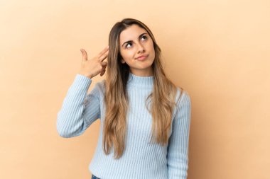 Genç beyaz kadın bej arka planda izole edilmiş ve intihar jesti yapmada sorun yaşıyor.