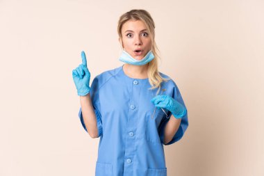 Diş hekimi kadının elinde, izole edilmiş bir arkaplanda şaşırtıcı bir yüz ifadesi var.