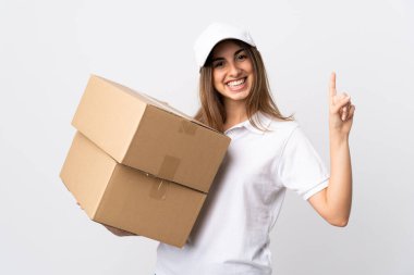 Tecrit edilmiş beyaz arka planda genç teslimatçı kadın en iyinin işareti olarak parmağını kaldırıyor ve gösteriyor.