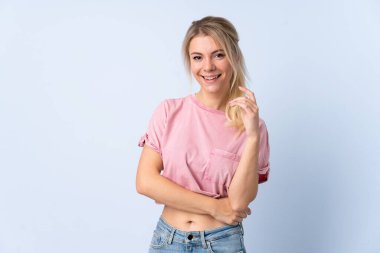 Sarışın kadın mavi arka planda gülüyor.