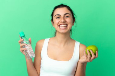 Yeşil arka planda, bir elma ve bir şişe suyla izole edilmiş beyaz bir kadın.