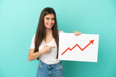 Mavi arka planda izole edilmiş beyaz bir kadın elinde büyüyen bir istatistik okunun sembolü olan bir tabela tutuyor ve onu işaret ediyor.