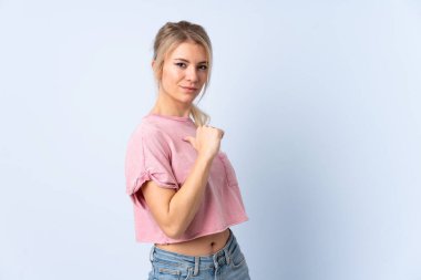 Sarışın kadın soyutlanmış mavi arka planda gururlu ve kendini beğenmiş