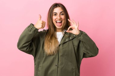 Soyutlanmış pembe arka planda genç bir kadın işaret ve işaret işareti gösteriyor.