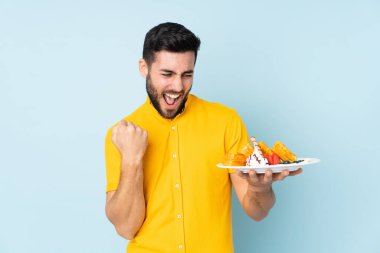 Mavi arka planda gözleme tutan beyaz adam zaferi kutluyor.