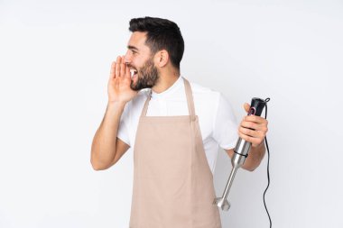 Beyaz arka planda izole edilmiş el blenderi kullanan adam ağzı açık bağırıyor.
