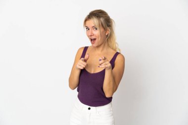 Beyaz arka planda izole edilmiş genç bir Rus kadın şaşırmış ve ön tarafı işaret ediyor.