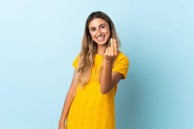 Soyutlanmış mavi arka planda genç İspanyol kadın para hareketi yapıyor.