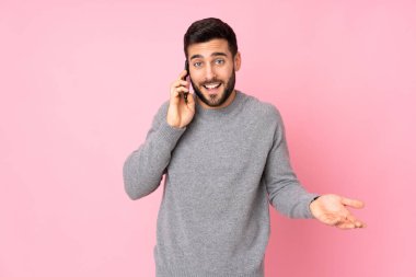 Kafkasyalı yakışıklı adam izole edilmiş arka planda cep telefonuyla sohbet ediyor.